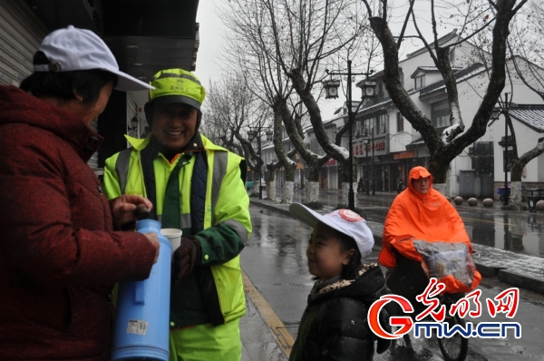 小女孩跟着奶奶为环卫工人送姜茶。 光明网苏州1月21日电(记者苏雁 通讯员魏巍)1月20日夜间,2016年的第一场雪降临苏城,整座城市都进入了速冻模式。 1月21日一早,双塔街道网师巷社区的几位热心居民带着满满两热水瓶的暖身姜枣茶走上十全街,请顶风冒雪坚守在一线的环卫工人、警务人员、修车师傅品尝,为他们送去了融融暖意。 9岁的小女孩周怡诺第一天放寒假,她的奶奶赵桂芳特地带她一起来给坚守在风雪中的人们送姜茶,看着漫天飞雪,小女孩很兴奋,对于寒假第一天自己做的这件有意义的事,她更自豪:天下着雪,