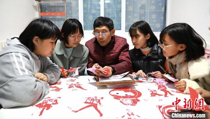 剪纸艺人冉占水和学生一起创作冬奥会运动项目全家福。　刘江涛 摄