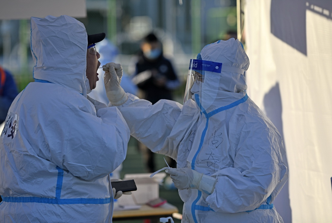 在天津市滨海新区泰达第二体育场核酸检测点，医务人员在为现场执勤的公安民警进行核酸采样（1月10日摄）。新华社记者 赵子硕 摄