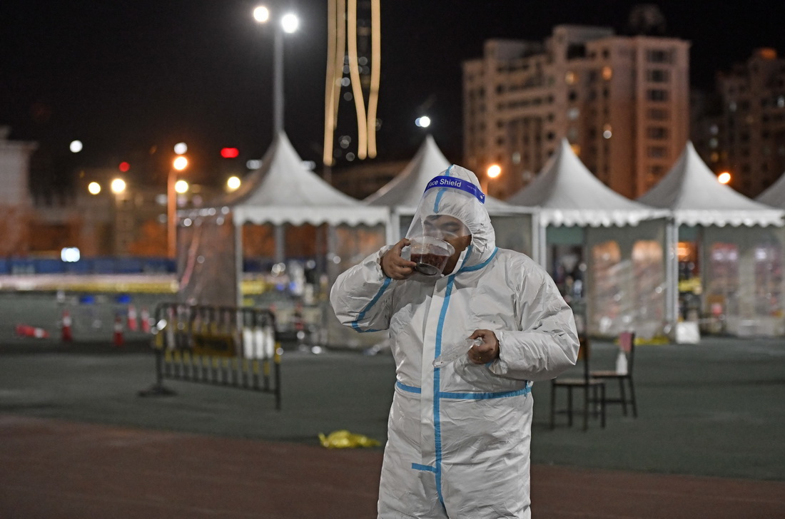 在天津市滨海新区泰达第一体育场核酸检测点，工作人员在工作间隙品尝腊八粥（1月10日摄）。新华社记者 赵子硕 摄