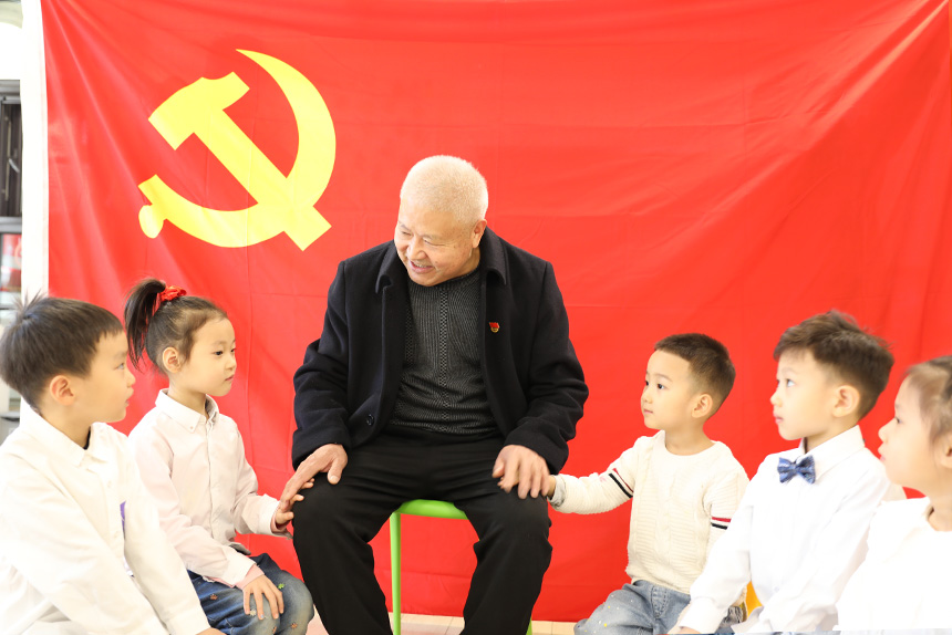 67岁老党员韩奎文在党旗下为孩子讲述革命故事。刘祺摄