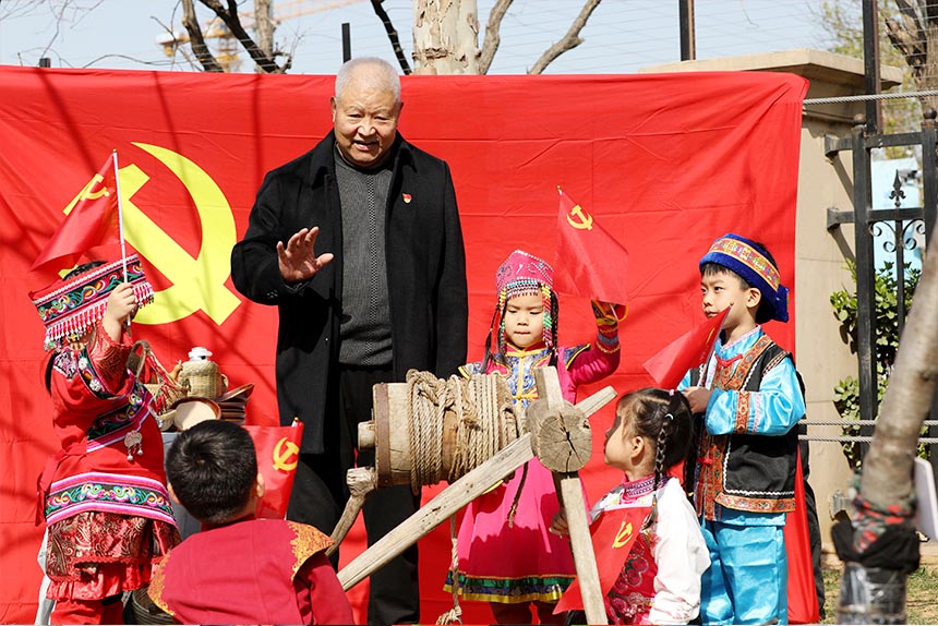 老党员韩奎文在辘轳井边，为孩子讲述《吃水不忘挖井》的红色革命故事。刘祺摄