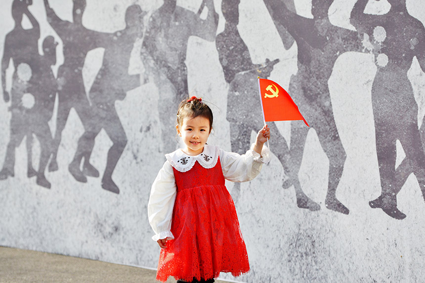 小朋友在红色剪影墙旁手举党旗，从小立下革命志，长大当好接班人。刘祺摄