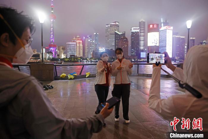 华中科技大学同济医学院附属同济医院援沪医疗队队员冒雨在外滩滨江步道上摆造型合影。　殷立勤 摄