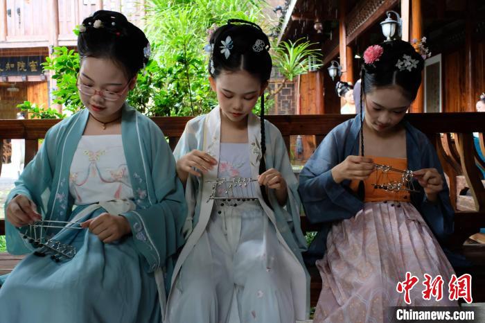 三名身穿汉服的女生正在把玩古代益智玩具——九连环。　刘俊聪 摄