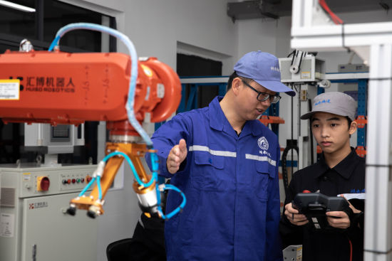 学校教师刘海龙指导学生进行工业机器人基础应用实训。