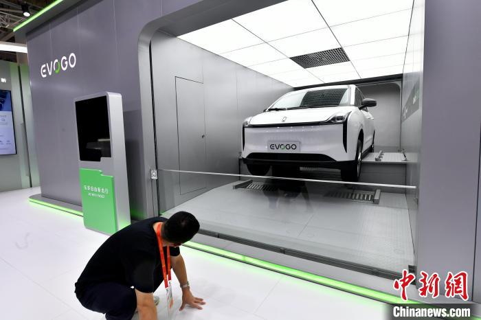 图为宁德时代展馆内展示的全自动电动汽车更换电池过程吸引参观者。　吕明 摄