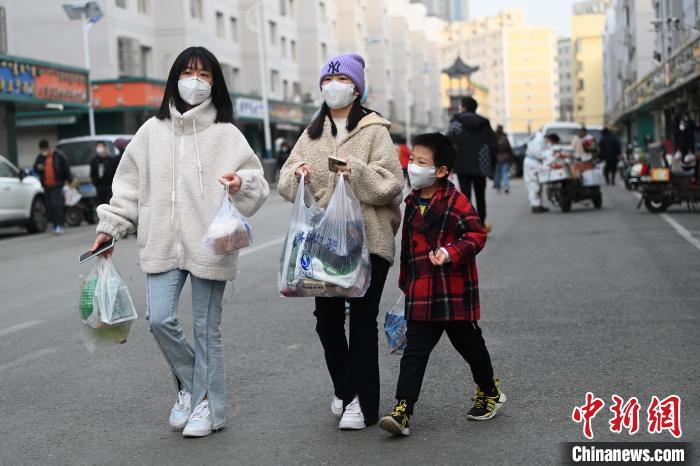 11月20日，内蒙古呼和浩特市，市民提着食品在街边步行。　刘文华 摄
