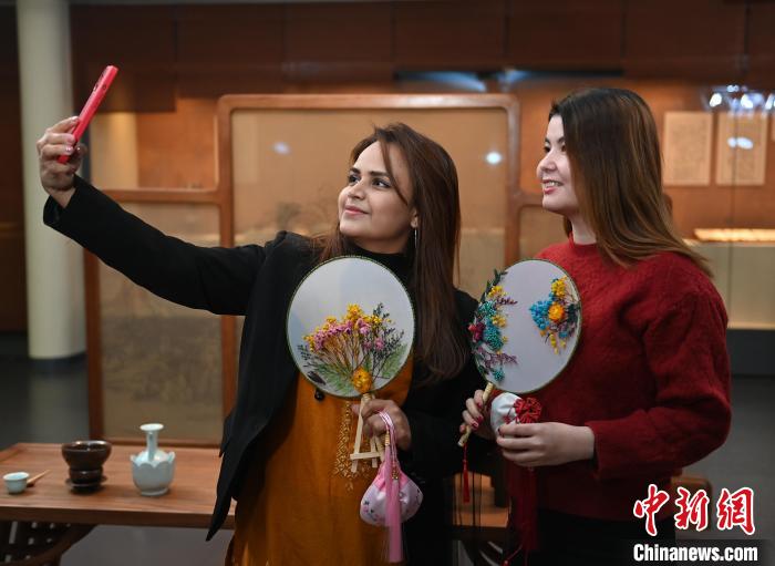 来自土库曼斯坦的留学生胡天美(右)和异国好友体验中国传统文化。　张瑶 摄