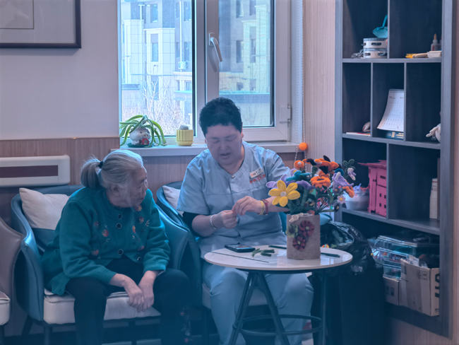 老人在和工作人员学习编织花。人民网记者 马俊华摄