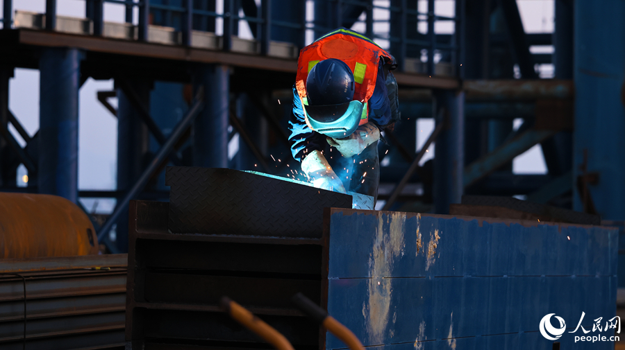 建设者正在专注施焊，为跨海工程筑牢根基，现场焊花四溅。人民网记者 李昌乾摄
