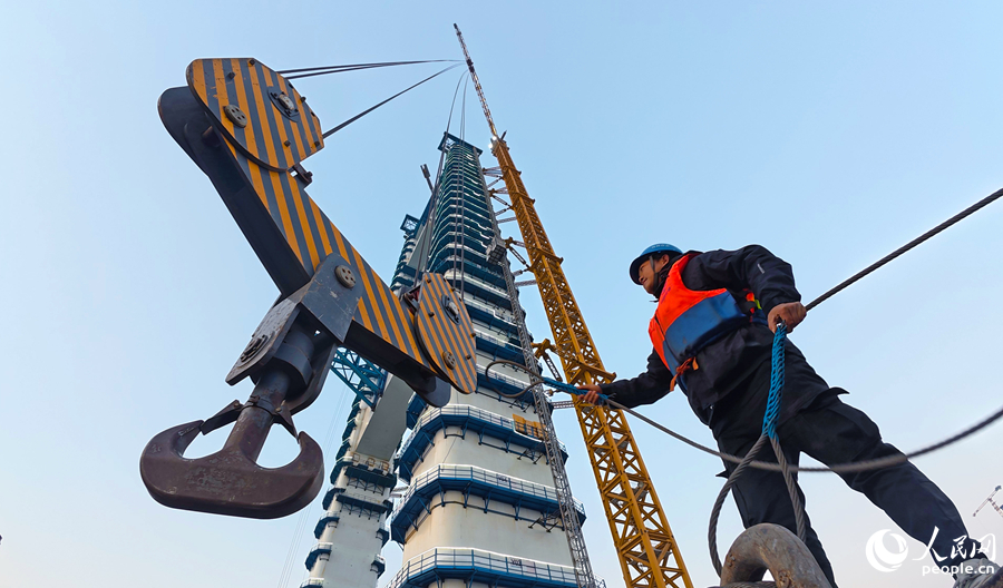 建设者正配合塔吊吊装作业。人民网记者 李昌乾摄