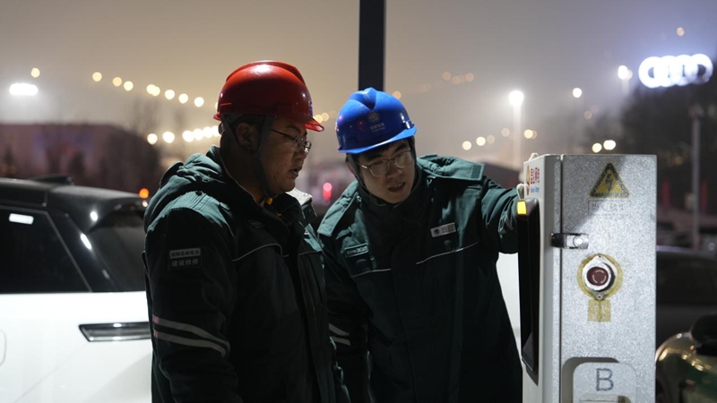 吉林供电公司北大湖供电所李泓申和富群敬在北大湖滑雪场停车场检查电动汽车充电桩。