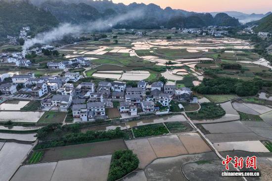 5月13日，航拍贵州省黔西南布依族苗族自治州兴义市万峰林水田。时下，万峰林水田迎来注水、插秧时节。从空中俯瞰，水田宛如天然“调色板”，与山峰、河流、村寨等融为一体，呈现出别样的田园风景。（无人机照片）中新社记者 瞿宏伦 摄