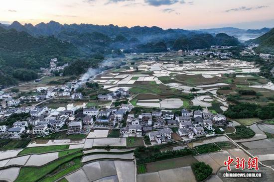 5月13日，航拍贵州省黔西南布依族苗族自治州兴义市万峰林水田。时下，万峰林水田迎来注水、插秧时节。从空中俯瞰，水田宛如天然“调色板”，与山峰、河流、村寨等融为一体，呈现出别样的田园风景。(无人机照片)中新社记者 瞿宏伦 摄