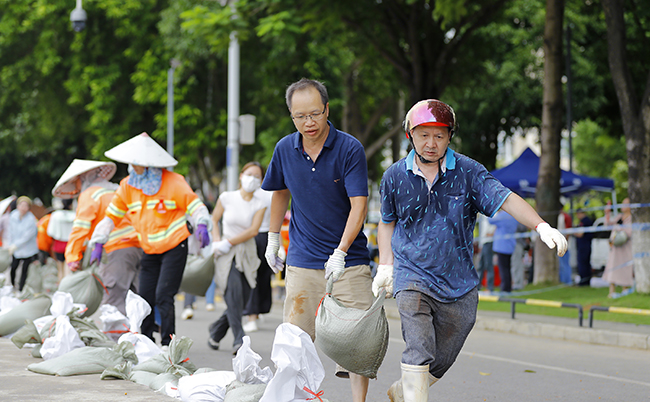 面对汛情，当地环卫工人、党员、干部及周边群众自发组织应急队伍搬运沙袋，在文化广场临水一侧构筑临时挡水设施。卢文斐摄
