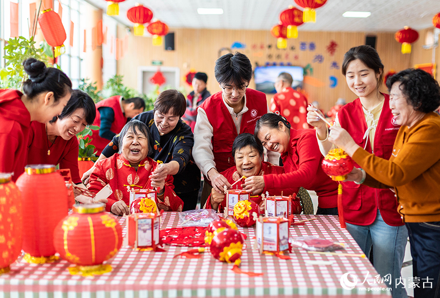 呼和浩特市玉泉区民政局的工作人员、志愿者与老人们一起制作花灯。丁根厚摄