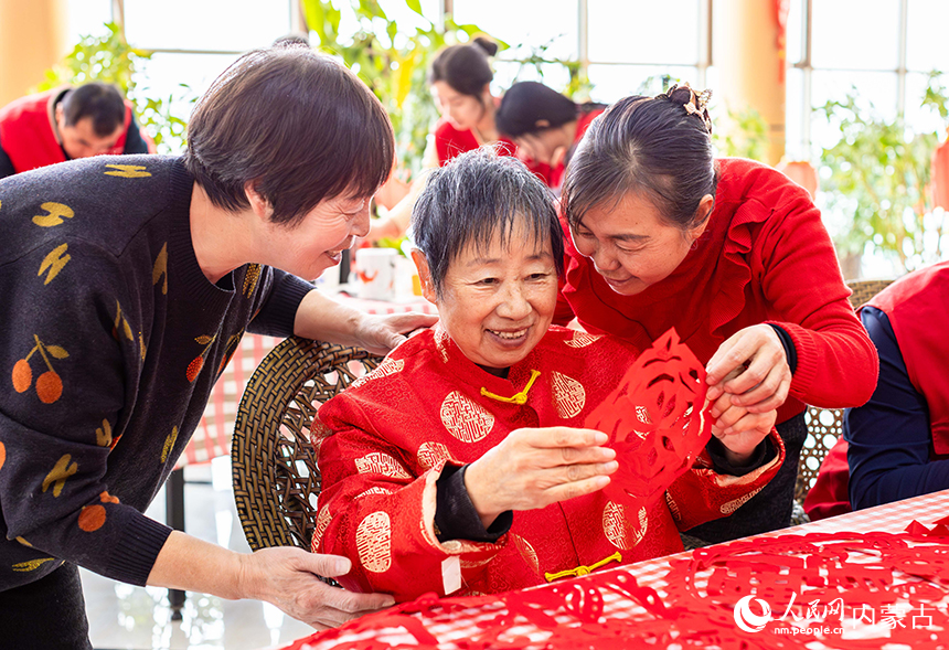呼和浩特市玉泉区民政局的工作人员、志愿者与老人们一起剪窗花。丁根厚摄