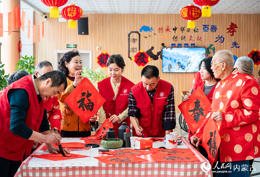 呼和浩特市玉泉区民政局的文化志愿者为老人们写“福”字送祝福。丁根厚摄
