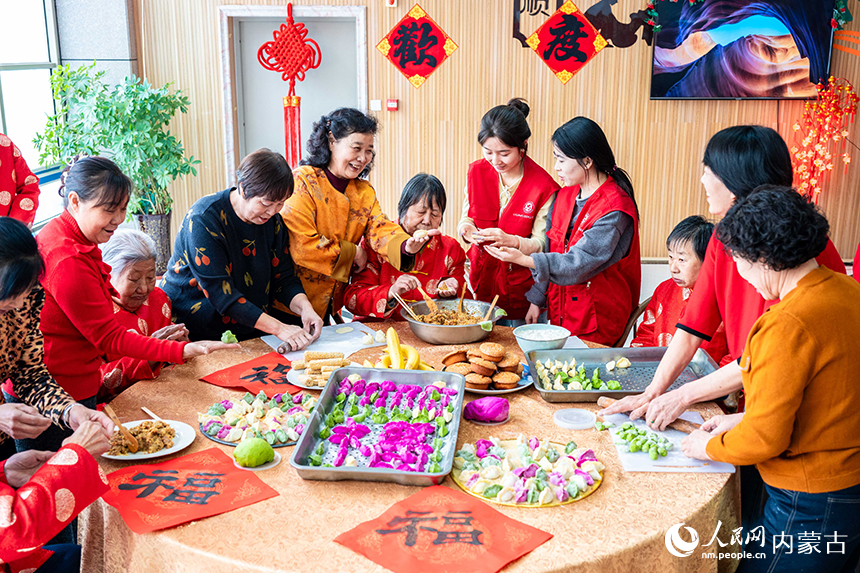 呼和浩特市玉泉区民政局的工作人员、志愿者与老人们一起包饺子。丁根厚摄