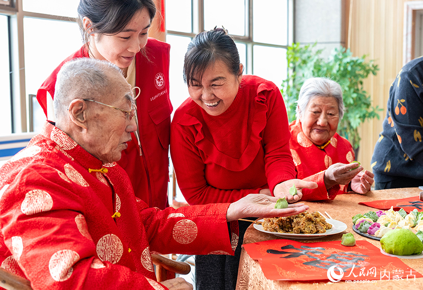呼和浩特市玉泉区民政局的工作人员、志愿者与老人们一起包饺子。丁根厚摄